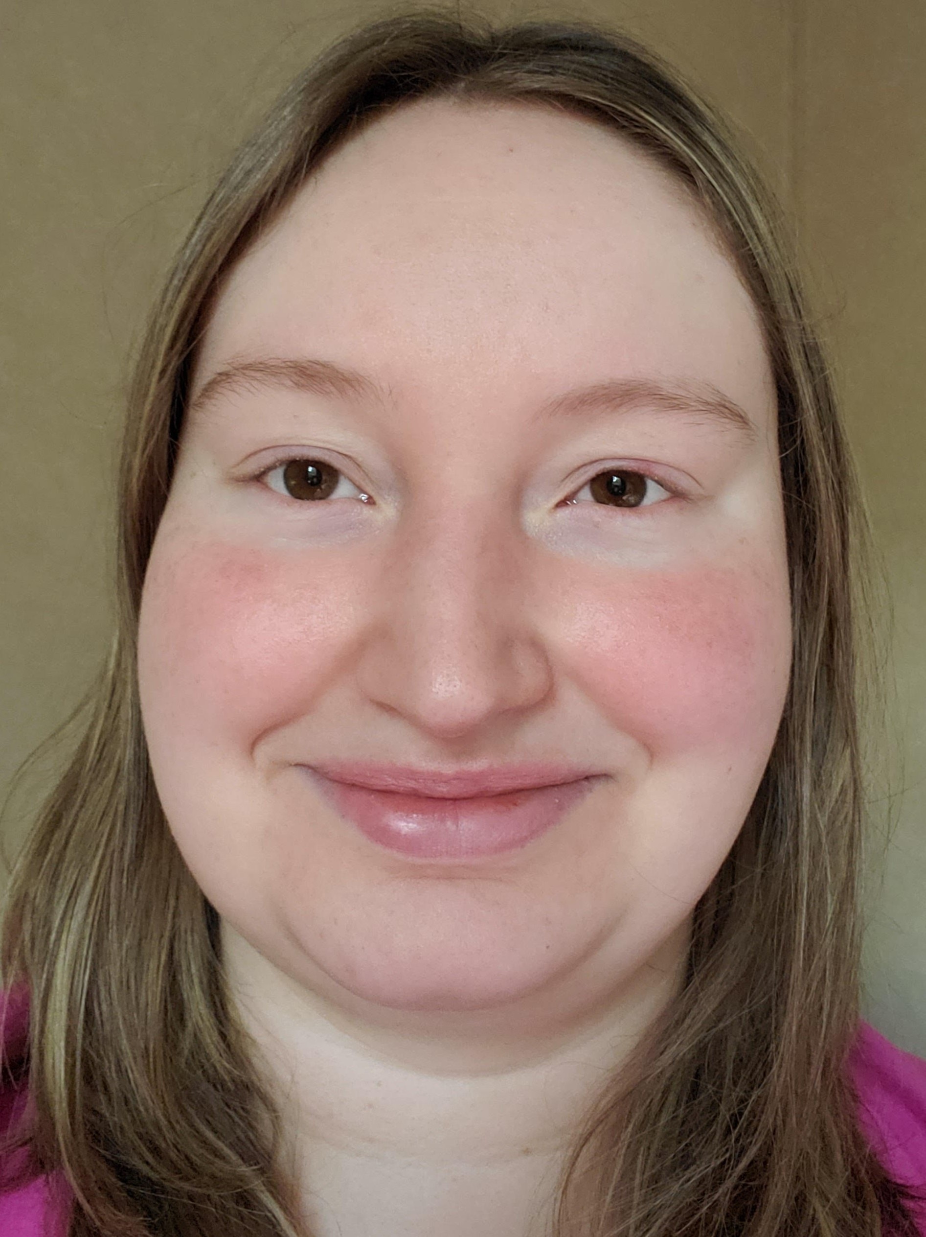 Portrait of a woman with light brown hair, smiling gently at the camera against a neutral background.
